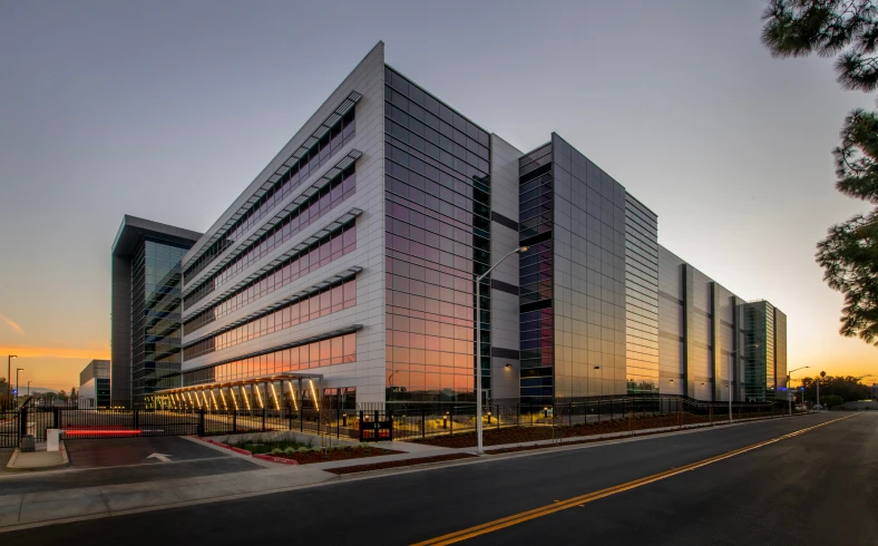 Modern glass building at sunset, road view.